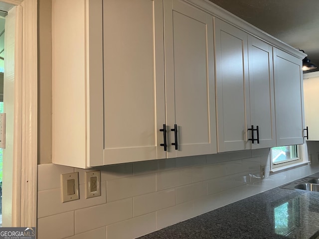 room details with dark stone countertops, backsplash, and white cabinets