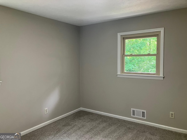 empty room with visible vents, baseboards, and dark colored carpet