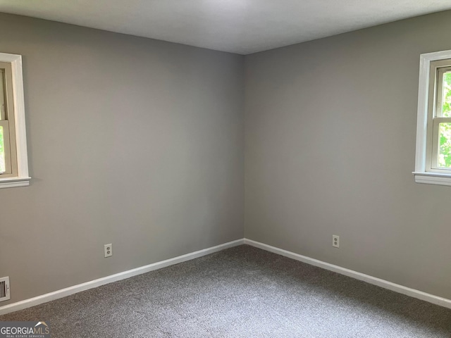 empty room with carpet floors, baseboards, and visible vents