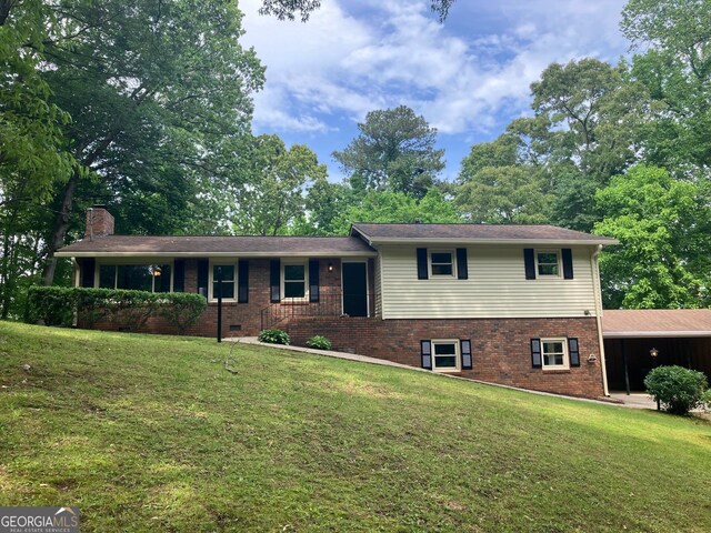tri-level home featuring brick siding, a chimney, and a front lawn