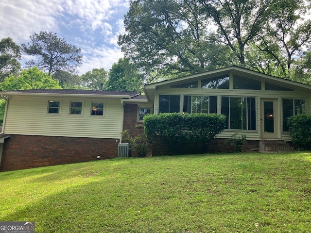 exterior space featuring a yard, central AC, and brick siding