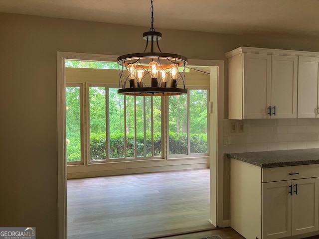 unfurnished dining area featuring an inviting chandelier and wood finished floors
