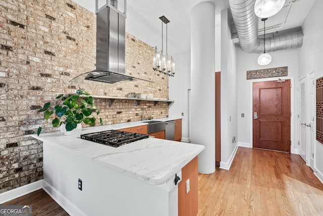 3820 Roswell Rd NE Unit 705, Atlanta, GA 30342 - kitchen with wall chimney exhaust hood, a peninsula, a sink, decorative backsplash, and light wood-style floors