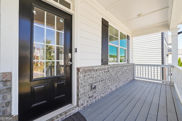 doorway to property featuring covered porch and brick siding