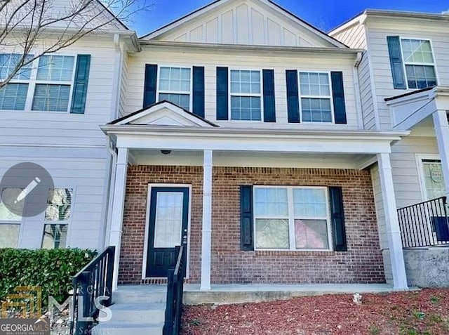 townhome / multi-family property with covered porch, board and batten siding, and brick siding