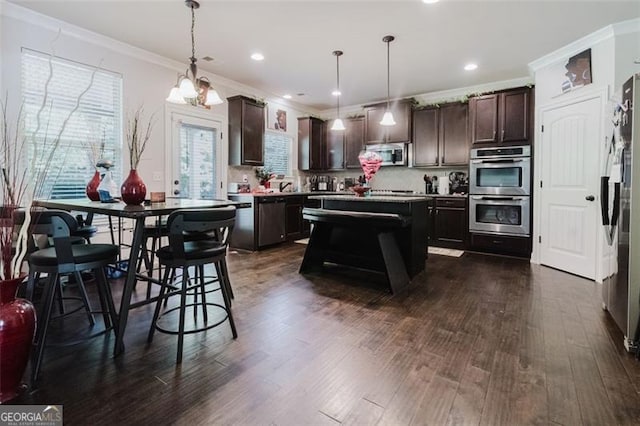 kitchen with ornamental molding, a wealth of natural light, dark brown cabinets, and stainless steel appliances