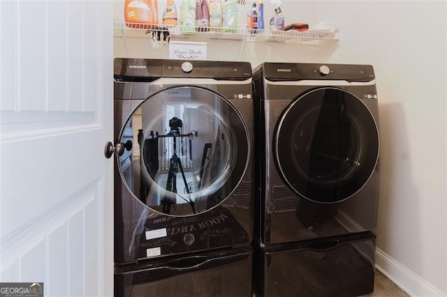clothes washing area with washer and dryer, laundry area, and baseboards