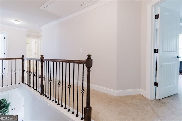 hallway featuring ornamental molding, baseboards, attic access, carpet flooring, and an upstairs landing