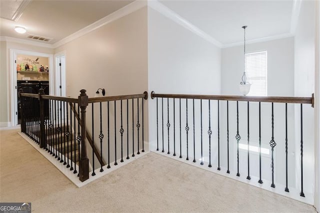 corridor featuring attic access, visible vents, ornamental molding, and carpet