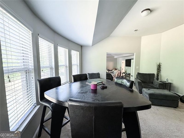 dining area featuring vaulted ceiling and carpet