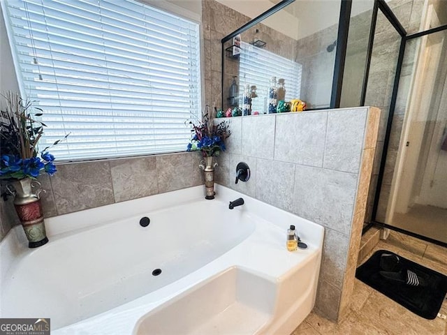 bathroom with tile patterned flooring, a shower stall, and a garden tub