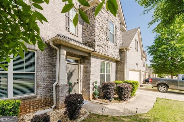 view of exterior entry with brick siding and a garage