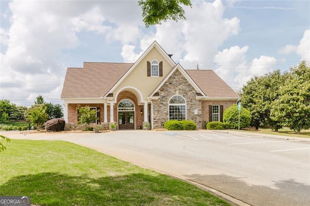 craftsman house with a front lawn, uncovered parking, french doors, and stone siding