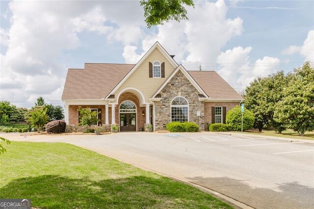 3241 Alhambra Cir, Hampton, GA 30228 - view of front of house featuring stone siding, uncovered parking, a front yard, and french doors