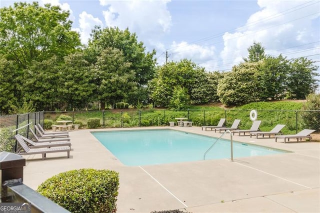 community pool with fence and a patio area