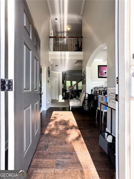 foyer featuring dark wood-type flooring, arched walkways, and a towering ceiling