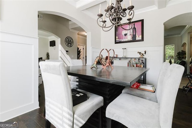 dining space featuring arched walkways, a chandelier, dark wood-type flooring, ornamental molding, and stairway
