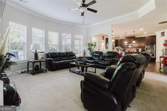 living room with plenty of natural light, ceiling fan, light carpet, and crown molding