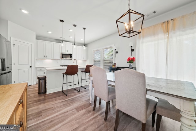 dining room featuring recessed lighting, a notable chandelier, visible vents, and light wood finished floors