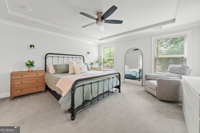 bedroom featuring a ceiling fan, visible vents, light colored carpet, baseboards, and a tray ceiling