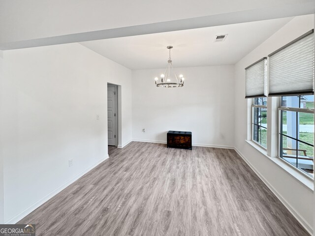 unfurnished dining area with baseboards, visible vents, wood finished floors, and an inviting chandelier