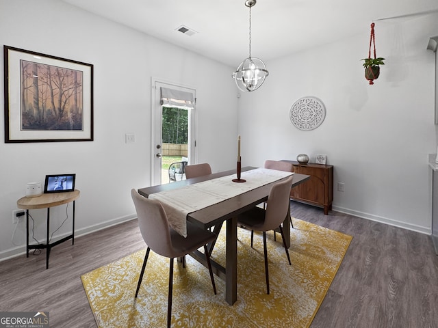 dining area with visible vents, baseboards, wood finished floors, and a chandelier