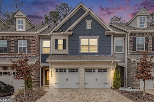 townhome / multi-family property featuring board and batten siding, an attached garage, decorative driveway, and brick siding