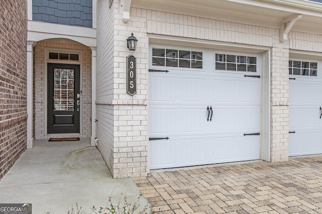 view of exterior entry with brick siding and a garage