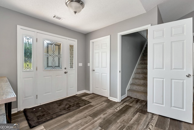 150 Buckeye Trails Dr, Commerce, GA 30530 - foyer entrance with dark wood-style flooring, a textured ceiling, visible vents, stairway, and baseboards