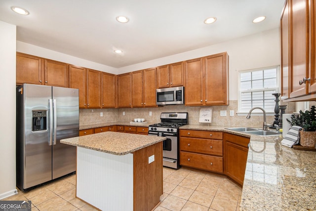 kitchen featuring brown cabinetry, decorative backsplash, a sink, light tile patterned floors, and stainless steel appliances