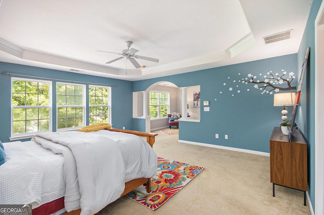 bedroom featuring visible vents, arched walkways, baseboards, a tray ceiling, and carpet flooring