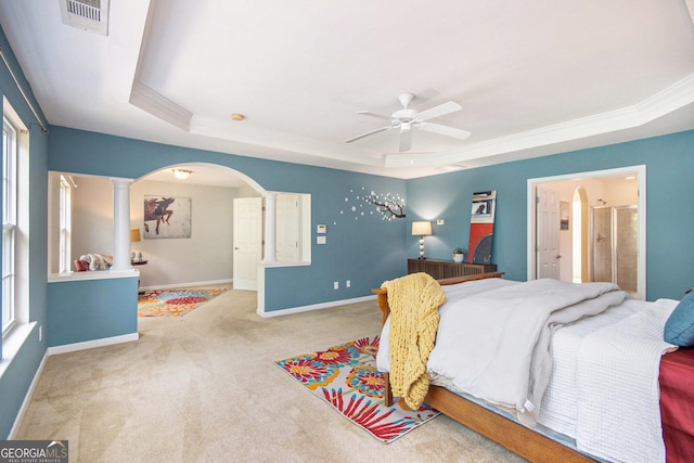 carpeted bedroom featuring visible vents, ornamental molding, baseboards, a tray ceiling, and arched walkways