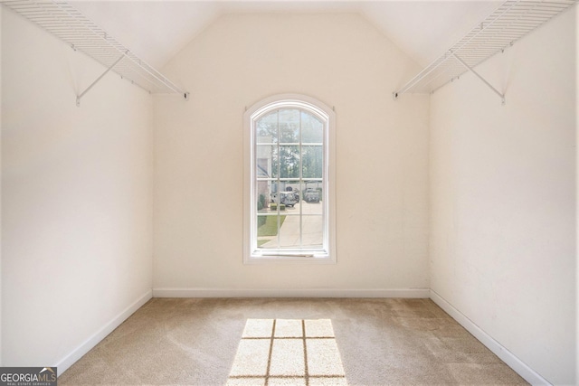 spacious closet featuring light colored carpet and lofted ceiling