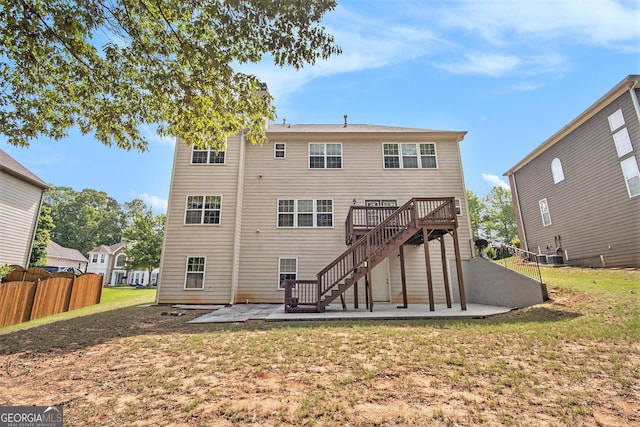 back of house featuring a lawn, a patio, fence, and stairs