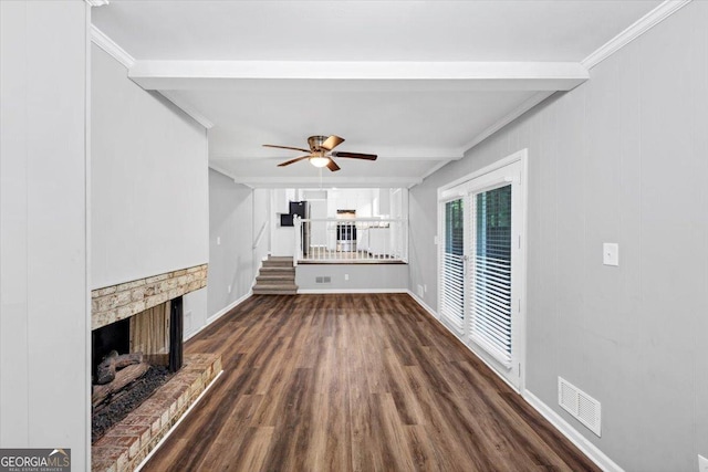 unfurnished living room with a ceiling fan, visible vents, crown molding, a fireplace with raised hearth, and dark wood-style floors