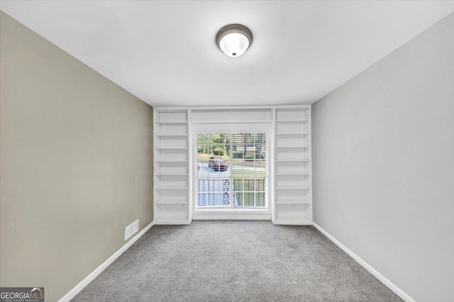 spare room with built in features, baseboards, carpet, and visible vents