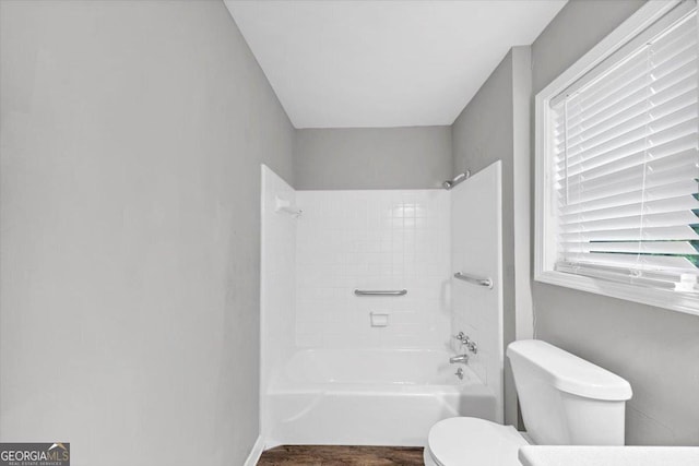 bathroom with toilet, tub / shower combination, and wood finished floors