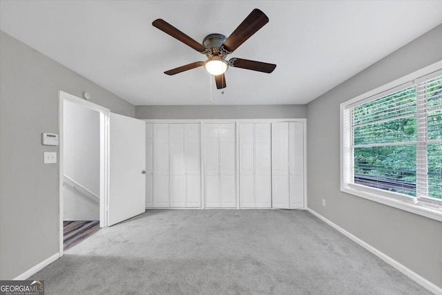 unfurnished bedroom with baseboards, carpet flooring, and a ceiling fan