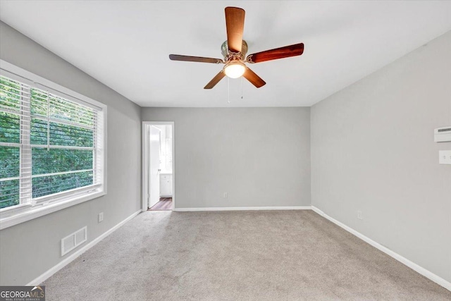 carpeted spare room with baseboards, a ceiling fan, and visible vents