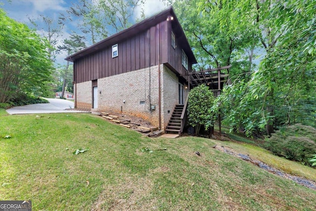 view of side of home featuring brick siding, board and batten siding, stairway, crawl space, and a lawn