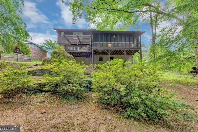 rear view of house featuring a sunroom, fence, and a deck