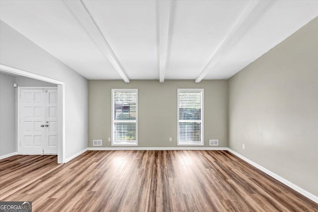 unfurnished room featuring baseboards, visible vents, and wood finished floors