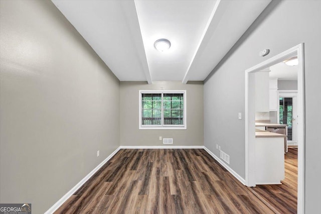 unfurnished room featuring baseboards, dark wood-style floors, and visible vents