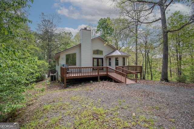 rear view of property featuring french doors, a wooden deck, a chimney, and metal roof