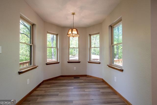 empty room with baseboards, wood finished floors, and a notable chandelier