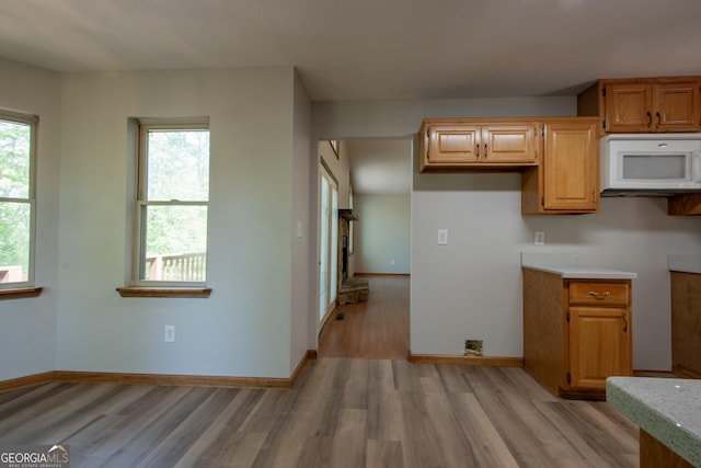kitchen with light wood-type flooring, baseboards, and white microwave