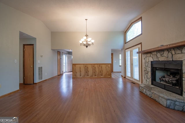 unfurnished living room featuring a fireplace, a chandelier, a wainscoted wall, wood finished floors, and visible vents