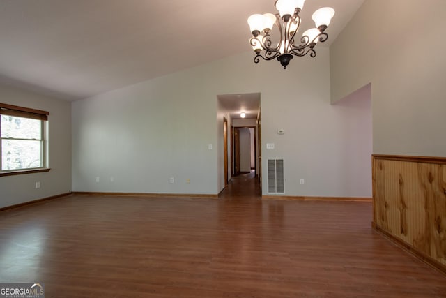 spare room featuring visible vents, lofted ceiling, wood finished floors, baseboards, and a chandelier