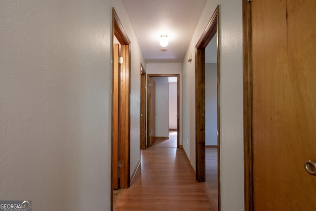 corridor featuring baseboards and light wood-type flooring