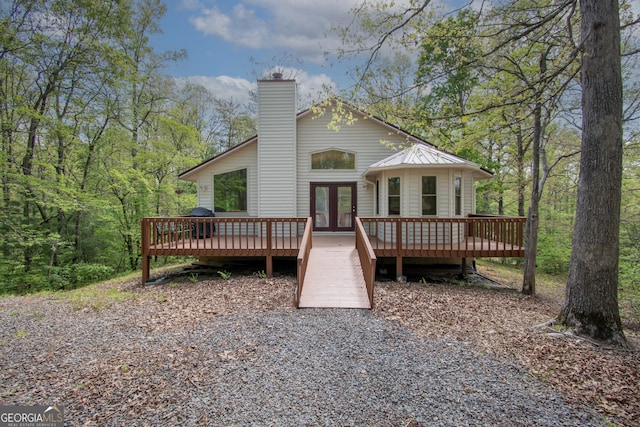 back of house with a deck, french doors, and a chimney